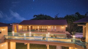 A two-story building with a balcony overlooking a grassy area, under a starry night sky. - The BaghVilla Pench FicusrootsExperience (Kurai)
