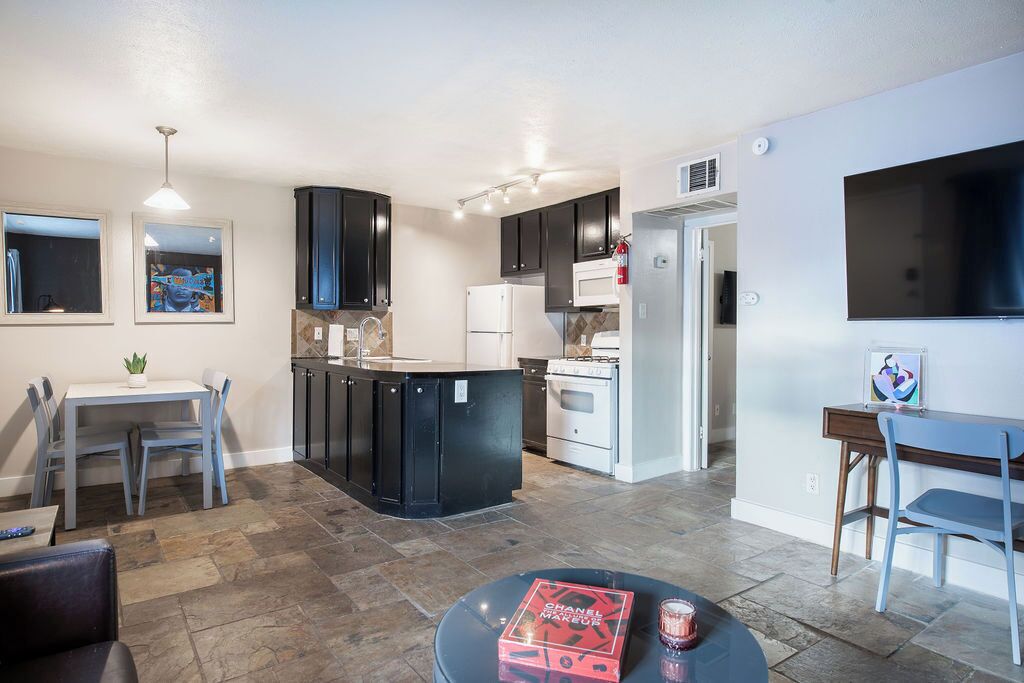 A modern kitchen with dark cabinets, a central island, and a dining area with a table and chairs.