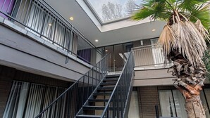 Ein modernes Gebäude mit einer zentralen Treppe, großen Fenstern und einer Palme.