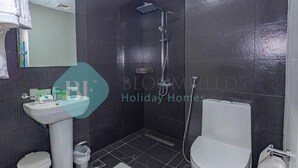 A bathroom with a pedestal sink, a toilet, a shower, and a mirror. - Bloomfields Modern 1Bedroom In Wavez (Dubai)