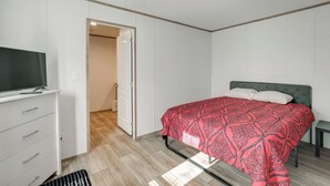 Una camera da letto con un letto, una TV su una cassettiera e una porta che dà su un'altra stanza.