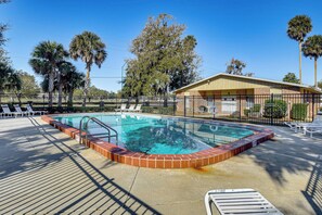 A rectangular swimming pool with a brick border, surrounded by a fence, and adjacent to a building with a sloped roof. - Sun, Sand & Poolside Relaxation! Ormond Beach Unit (Ormond Beach)