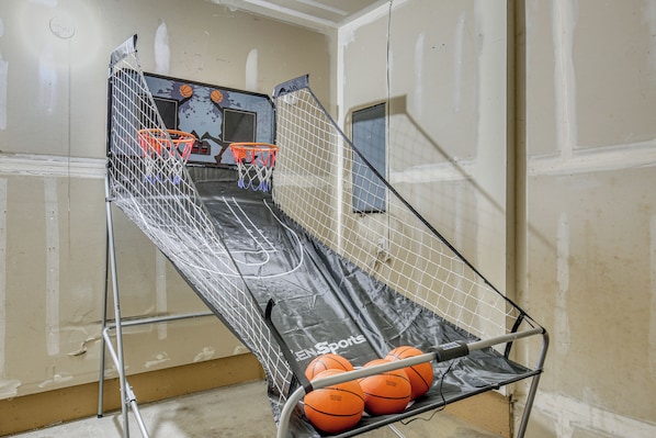 Un aro de baloncesto con red y tres balones de baloncesto sobre un soporte en una habitación con paredes sin terminar.
