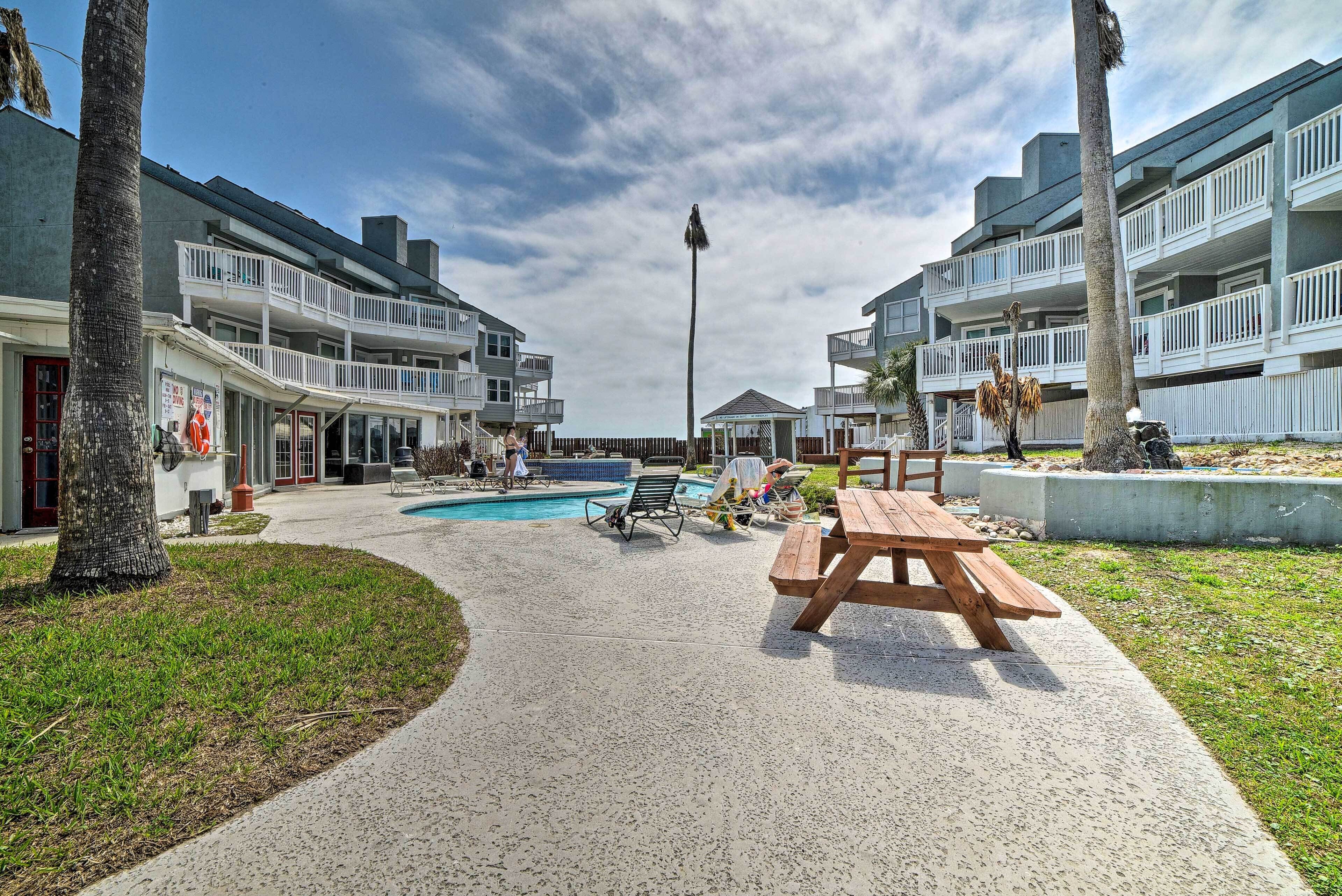 Ein Strandhotel mit Pool, Sitzgelegenheiten im Freien und einer Laube.