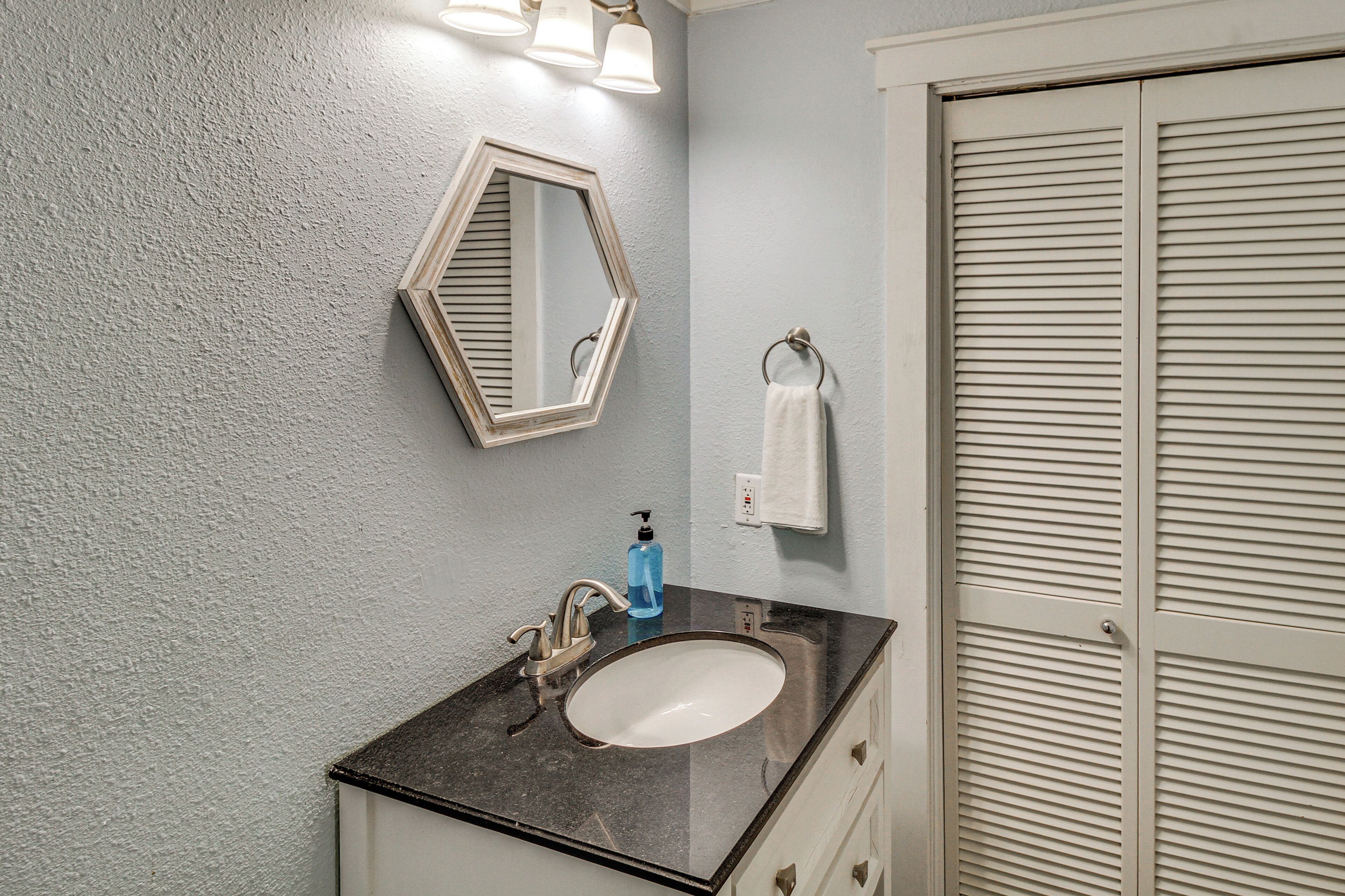 A bathroom with a sink, mirror, towel rack, and a closed door.
