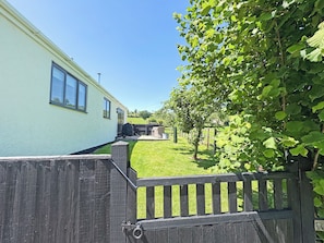 A residential property with a light-colored exterior, a wooden fence, and a grassy yard. - 1 bedroom accommodation in Bridport (Bridport)