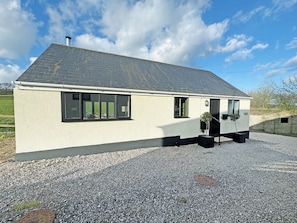 A single-story house with a sloped roof, a gravel driveway, and a small garden area with a potted plant. - 1 bedroom accommodation in Bridport (Bridport)