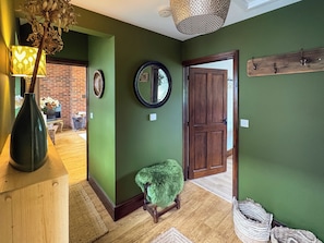 A hallway with green walls, a wooden door, a mirror, and a small stool. - 1 bedroom accommodation in Bridport (Bridport)