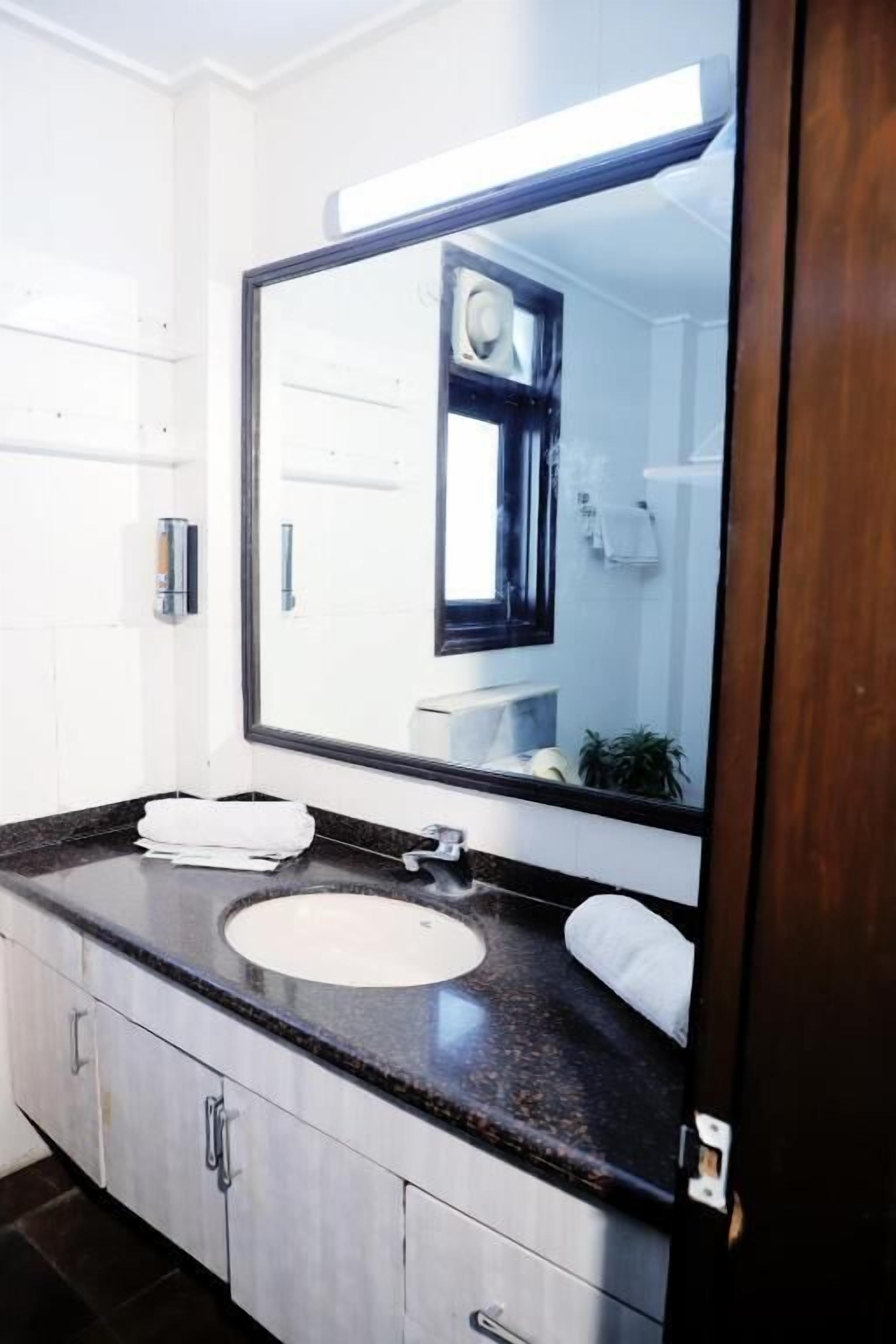A modern bathroom with a large mirror, a sink, and cabinets.