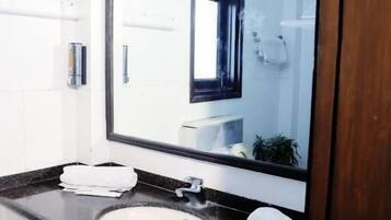 A modern bathroom with a large mirror, a sink, and cabinets.