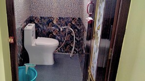 Een badkamer met toilet, douche en raam.