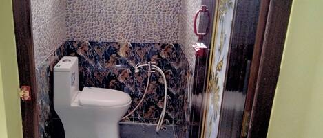 A bathroom with a toilet, a shower, and a window.
