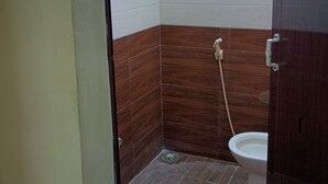Een badkamer met douche, toilet en raam.