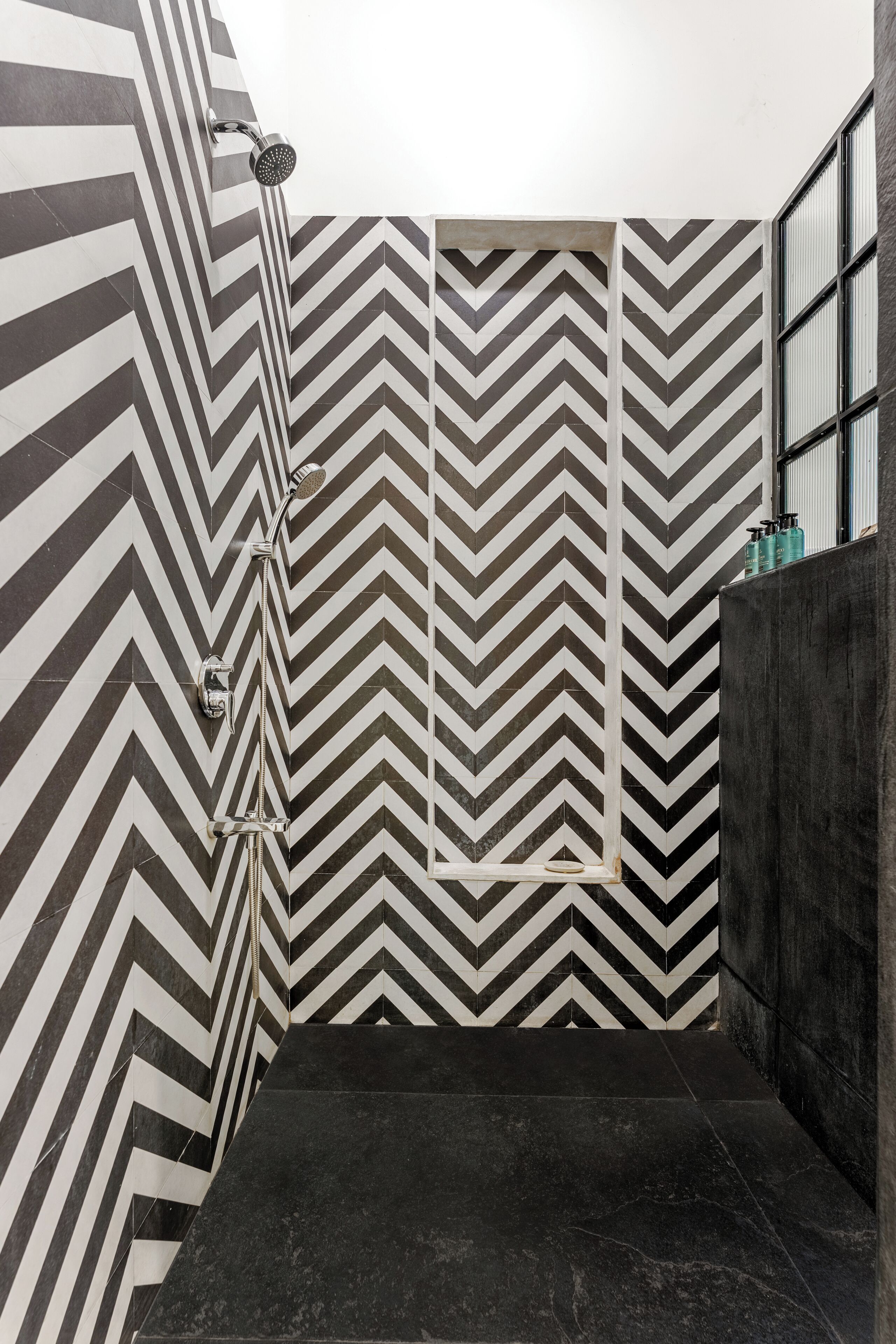 A modern bathroom with a black and white chevron tile pattern on the walls and floor.