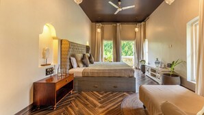 Quarto com uma cama grande, mesa de cabeceira, cômoda e janela com cortinas.