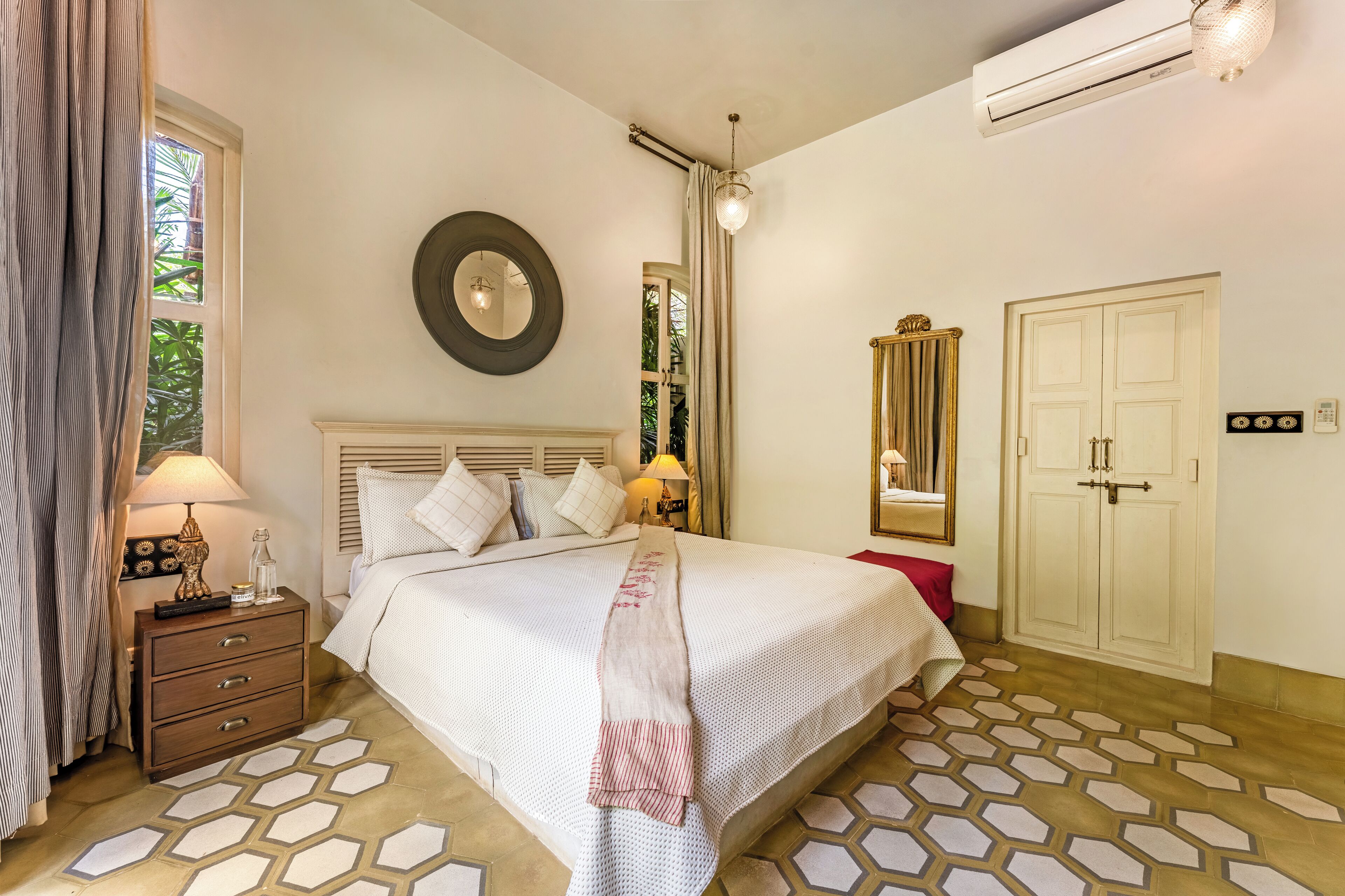 A neatly arranged bedroom with a bed, bedside tables, a mirror, and a wardrobe.