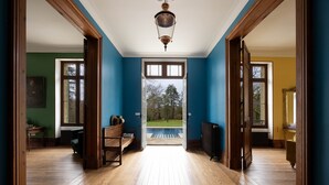 A hallway with wooden floors, a view of a pool, and a large open door leading outside. - Wild Elegance: A 120-Acre Forest & Château (Mouleydier)