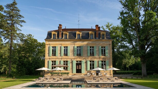 A large, multi-story building with a symmetrical facade, a central entrance, and a pool in the foreground. - Wild Elegance: A 120-Acre Forest & Château (Mouleydier)