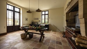 A spacious kitchen with a large table, hanging lights, and a fireplace.