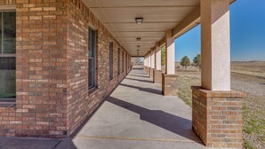 A covered corridor with brick walls and windows, leading to an open area with a clear view of the landscape. - Peaceful, Serene Getaway 17 Mi to Dtwn Roswell! (Roswell)