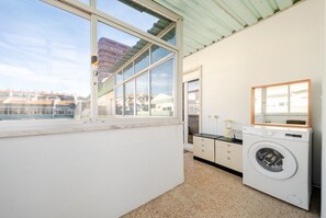 Un lavadero con lavadora, un lavabo pequeño y una ventana con vistas a una zona residencial.
