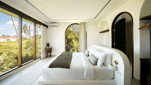 Quarto moderno com uma cama grande, vista para o exterior e armário embutido.
