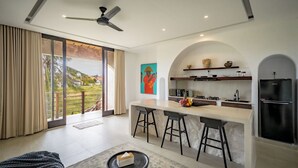 Uma cozinha moderna com uma ilha central, banquetas e uma geladeira.