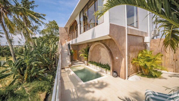 Uma casa moderna com piscina, palmeiras e uma escadaria que leva a uma varanda.
