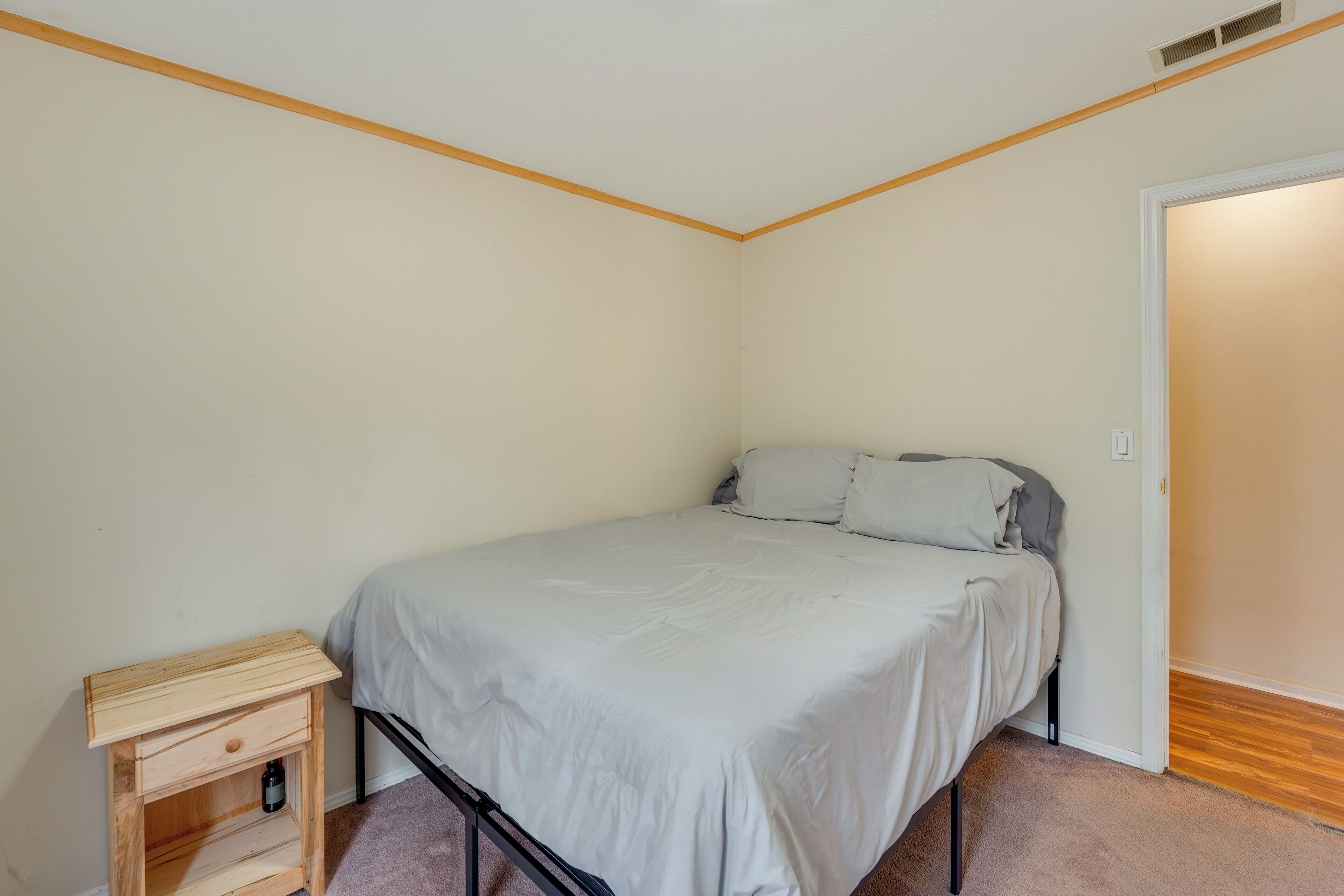 Une chambre à coucher avec un lit, une table de chevet et une porte donnant sur une autre pièce.