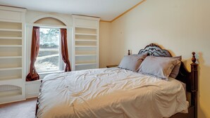 Une chambre à coucher avec un lit, une fenêtre avec des rideaux, une armoire intégrée et une tête de lit.