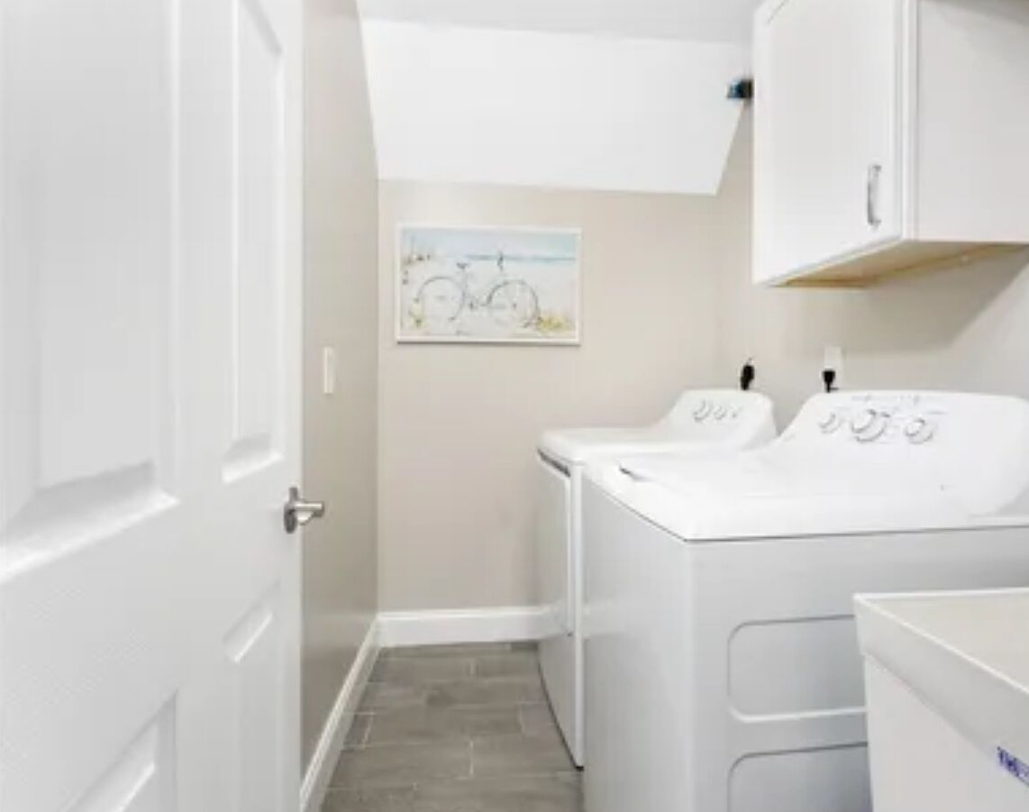 A laundry room with a washing machine, dryer, and a door leading to another room.