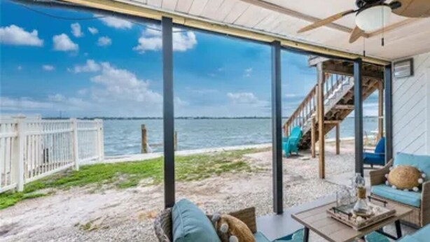 A covered outdoor seating area with wicker furniture, a ceiling fan, and a view of the beach and ocean. - Bayfront Condo, Prime Beach Access, Manasota Key (Englewood)