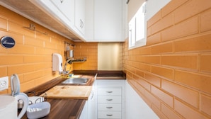 A compact kitchen with a wooden countertop, two sinks, and white cabinets. - Apartamento Encanto Gaditano con Terraza by C diz (Cádiz)