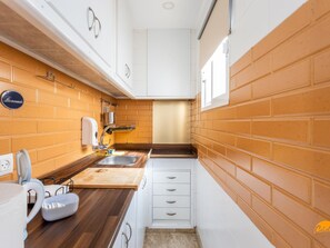 A compact kitchen with a wooden countertop, two sinks, and white cabinets. - Apartamento Encanto Gaditano con Terraza by C diz (Cádiz)