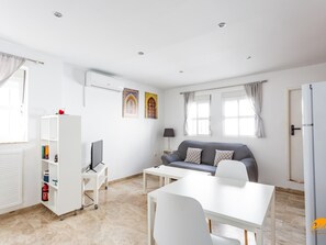 A modern living room with a grey sofa, white coffee table, and a white TV stand. - Apartamento Encanto Gaditano con Terraza by C diz (Cádiz)