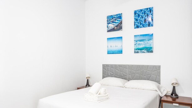 A hotel room with a bed, a nightstand, and a wall with four framed pictures. - Apartamento Encanto Gaditano con Terraza by C diz (Cádiz)