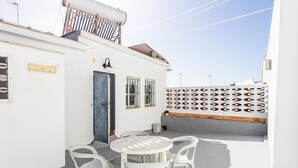 A white building with a blue door, a small balcony, and a white wall with circular patterns. - Apartamento Encanto Gaditano con Terraza by C diz (Cádiz)