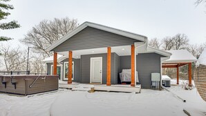 Ein modernes Haus mit überdachter Veranda, Whirlpool und einem von Schnee bedeckten Garten.