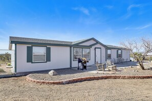 A single-story house with a covered patio, a gravel driveway, and a small garden area. - Magnolia Manor House: Desert Escape, Mtn Views (Dolan Springs)