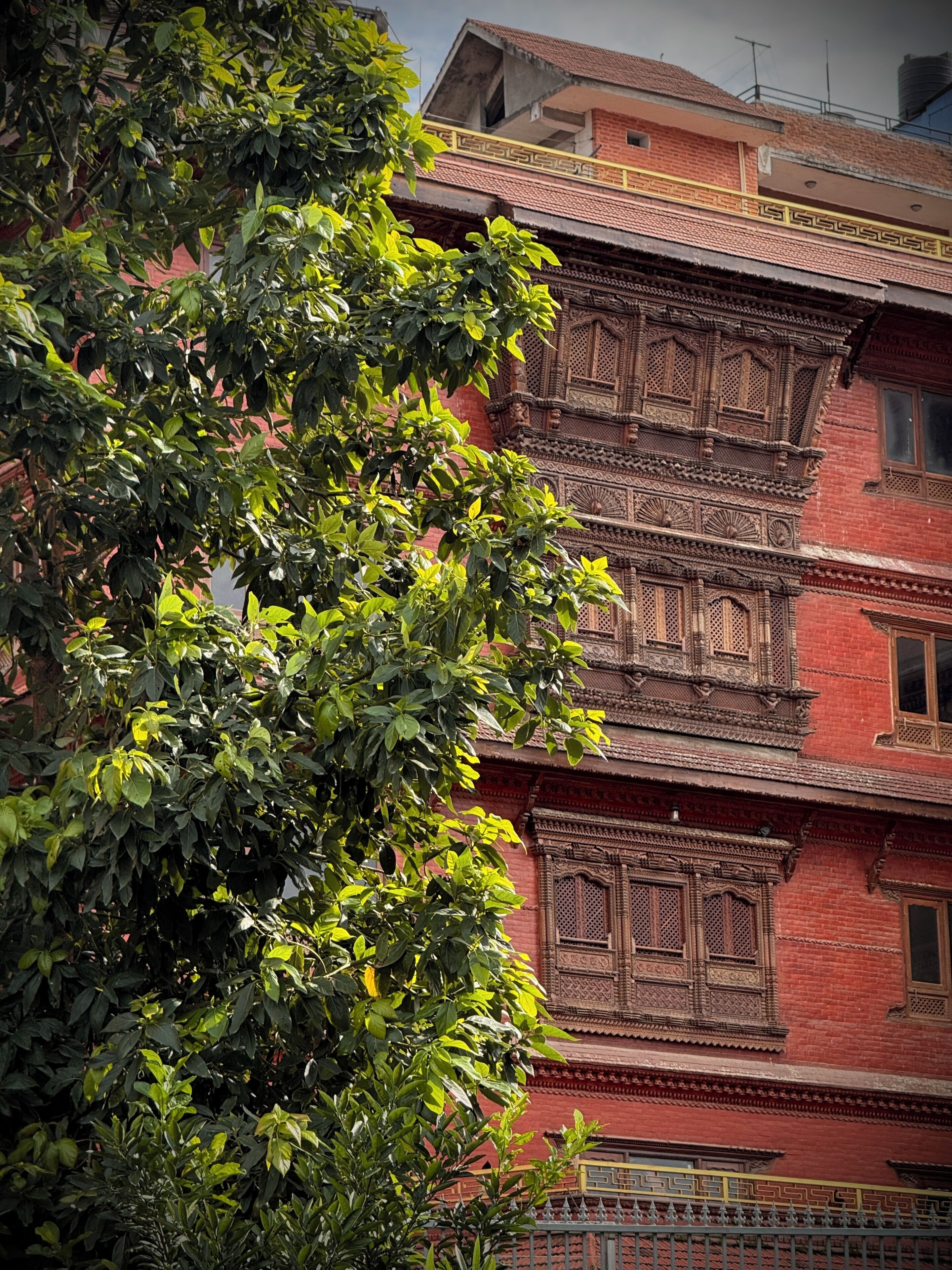 Un edificio de varios pisos con detalles arquitectónicos tradicionales, como balcones ornamentados y fachada de ladrillo rojo.