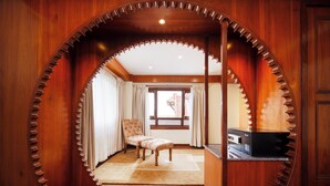 Una habitación con un marco de madera circular, una ventana, una silla y una pequeña mesa.