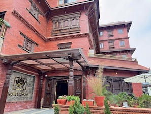 A traditional building with intricate wooden carvings, a sign reading 'HOTEL DACHI,' and potted plants in front. - Hotel Dachi Kathmandu - Bhaktapur (Bhaktapur)