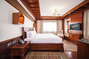 Une chambre d’hôtel avec un grand lit, un bureau avec un téléphone, une chaise, un téléviseur et un plafond en bois.