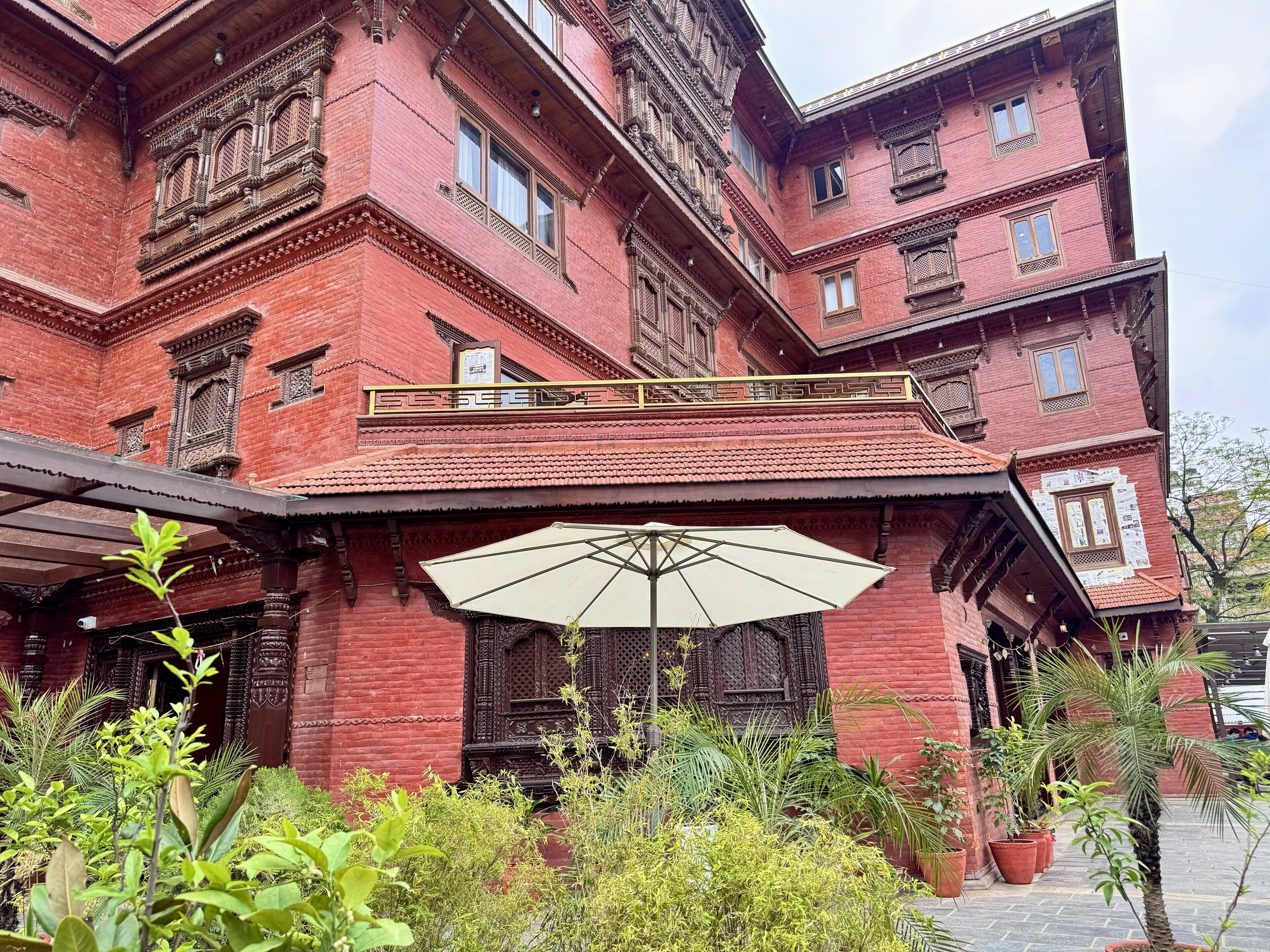 A red brick building with ornate balconies and a large umbrella.