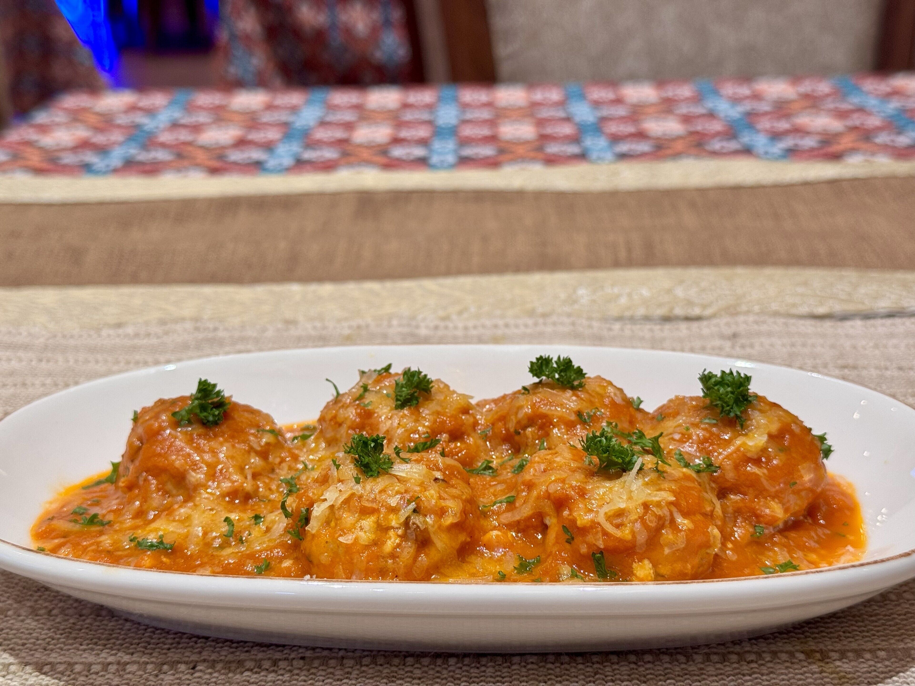 A plate of meatballs in tomato sauce garnished with parsley.