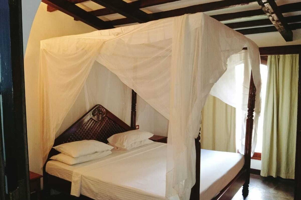 A four-poster canopy bed with a wooden frame and white bedding.