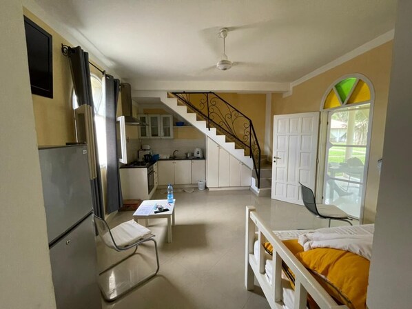 A compact hotel room with a kitchenette, a dining area, a bed, and a staircase leading to another level. - Mwembe Resort Malindi (Malindi)