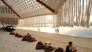 Uma praia com guarda-sol, areia e uma mesa com bebidas.