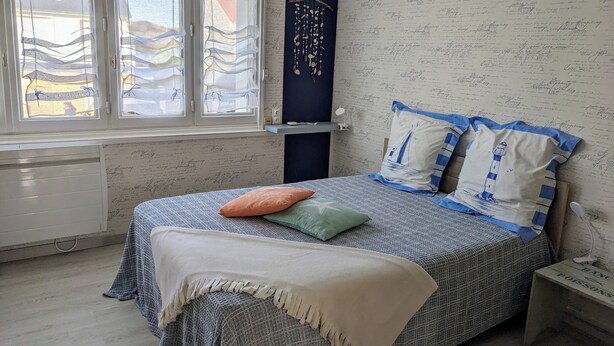 Een slaapkamer met een bed, een raam met gordijnen, een muur met handgeschreven aantekeningen en een nachtkastje.