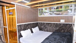 Una habitación de hotel con cama, zona de ducha y un mural de cascada.